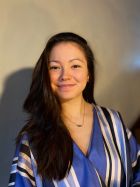 A young woman in blue smiles to camera 