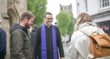 A priest speaks to two young people