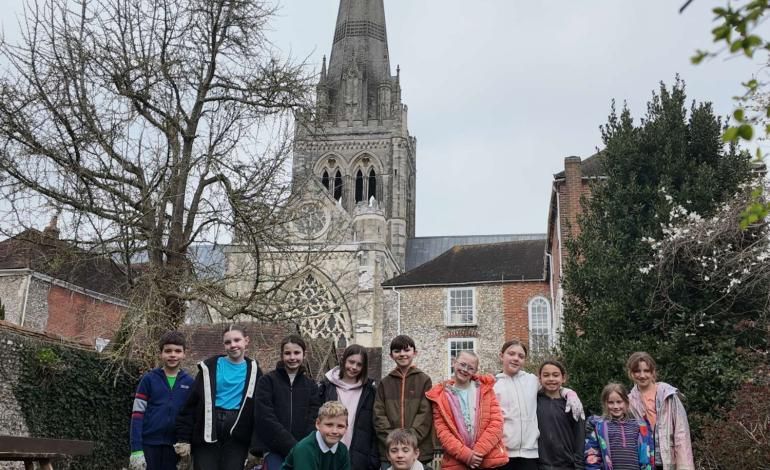 School children pose in a line in front of Chichester Cathedral