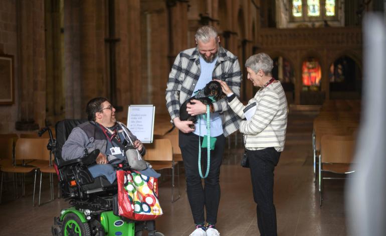 Two welcomers greet a visitor with a dog