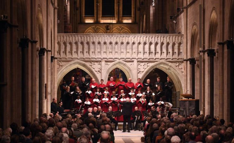 Chichester Cathedral Fundraising Concert in November 2025 with Sir John Rutter a choir stand in front of audience in front of cathedral architecture