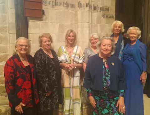 7 women in evening dress look to camera