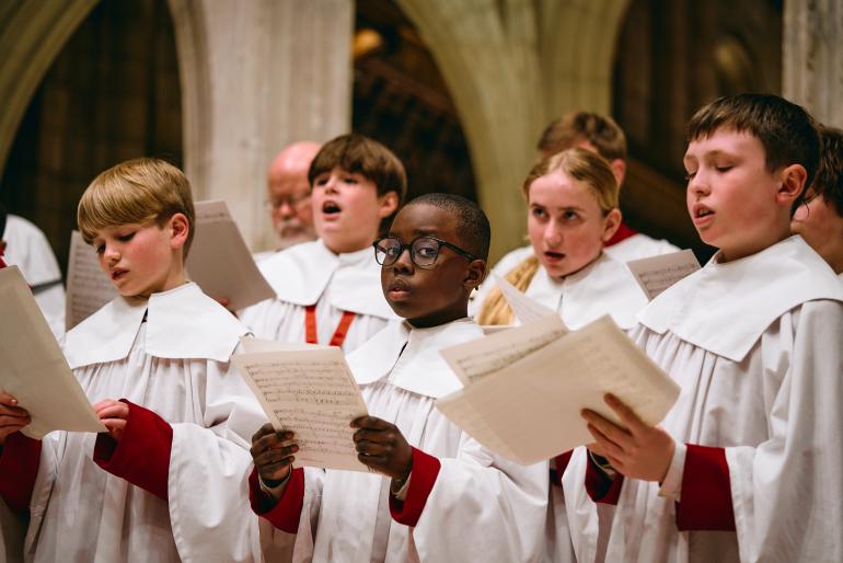 Cathedral Choristers sing whilst holding music sheets.
