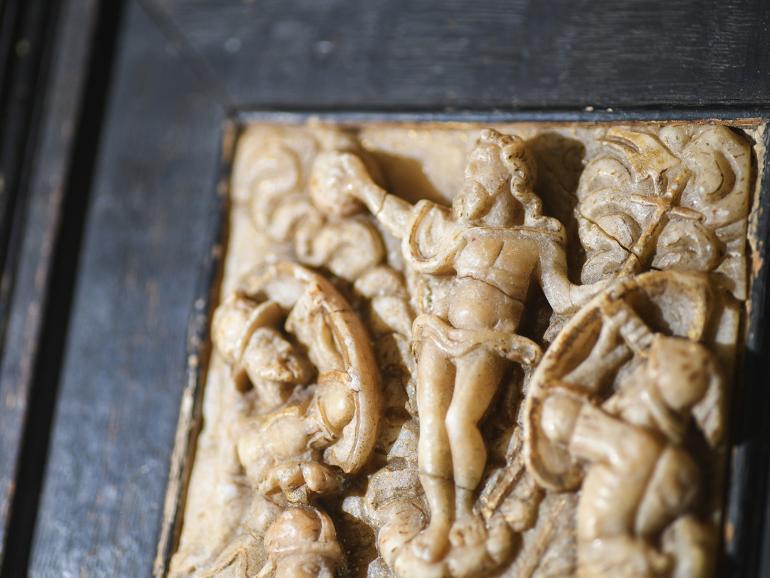 The top left corner of a beige, abaster relic depicting a risen Christ.