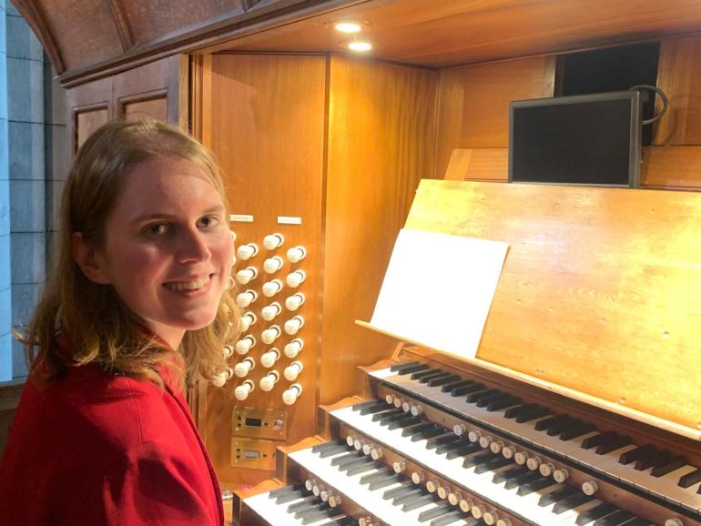 Stephanie Gaunt looks to camera and smiles, whilst sitting next to an organ keyboard