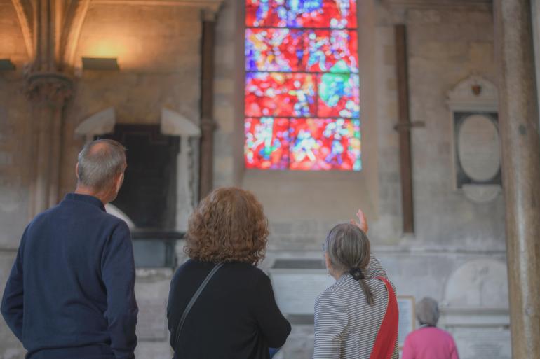 A guide shows a tour group the Chagall window, which has vibrant red stained glass