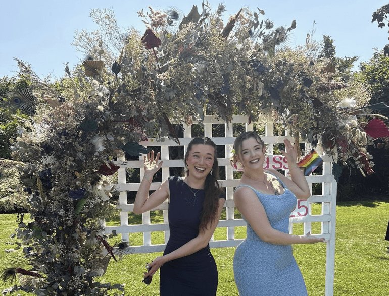Nancy Hersey and Lauren Dendy underneath flower arch
